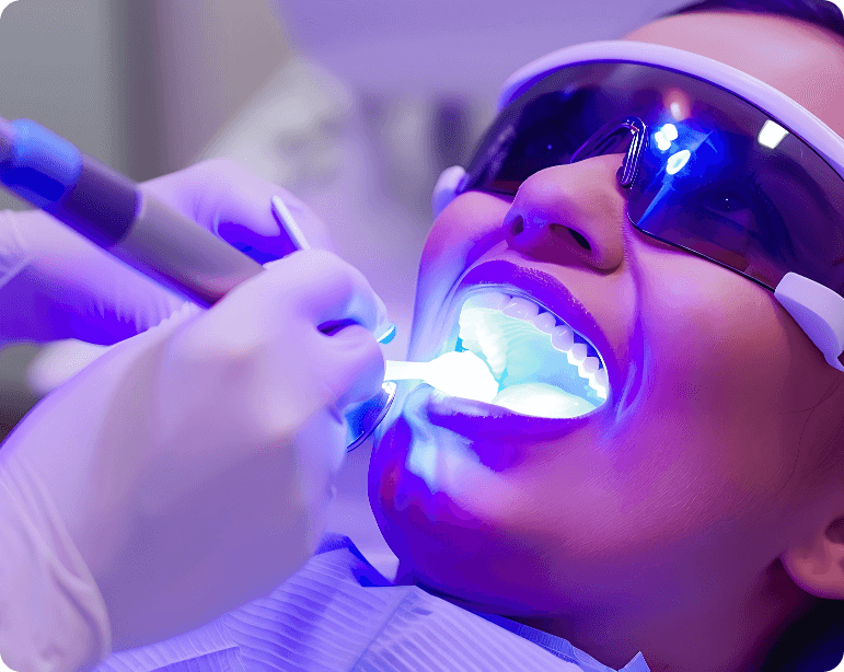 Closeup Woman Having Her Teeth Whitened With Blue Light She Is Wearing Protective Glasses Dentist Is Holding Tool Their Hand